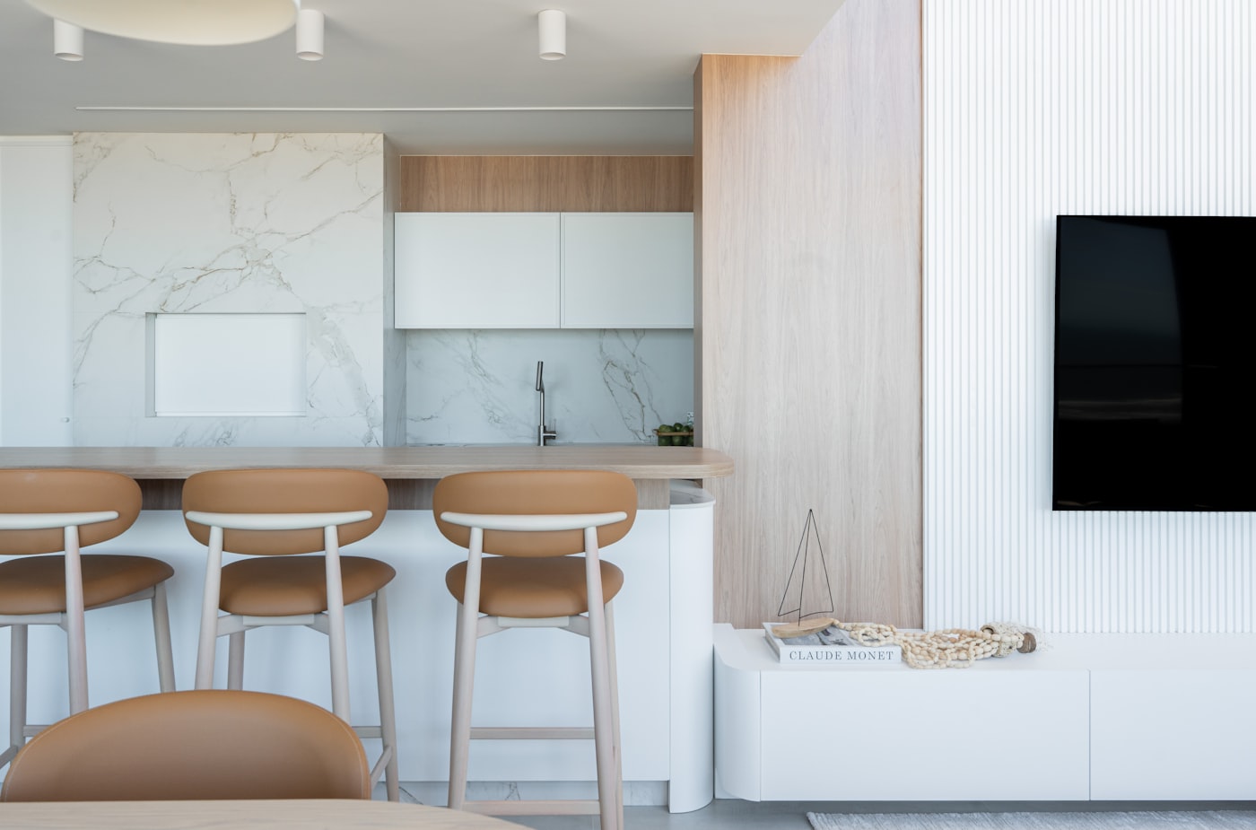 Sala integrada à cozinha, com bancada de refeições, painel ripado branco e marcenaria em madeira clara