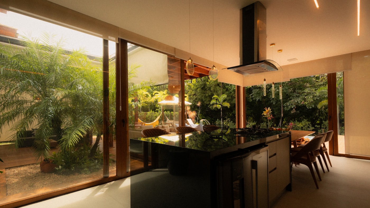Cozinha com ilha central em pedra, marcenaria sob medida e vista para o jardim